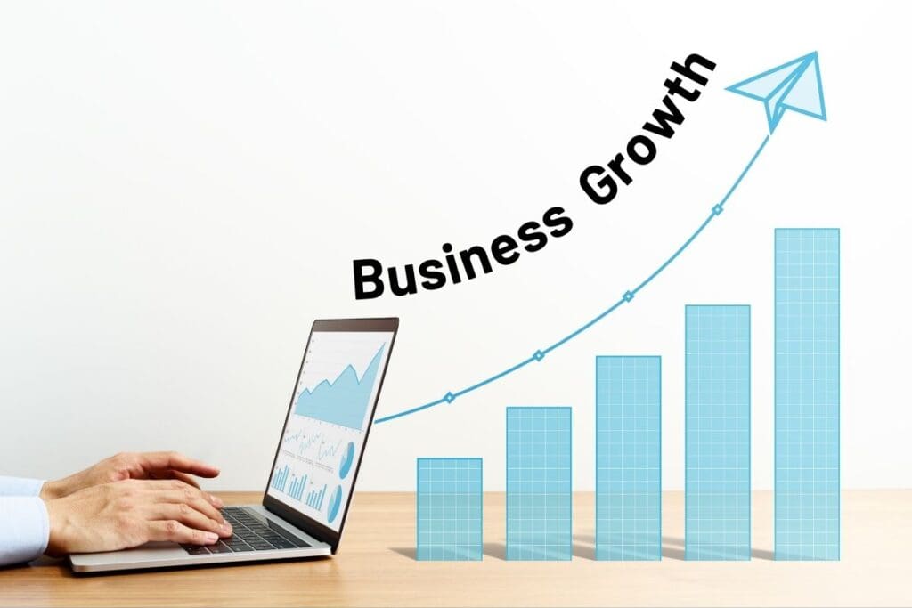 Photo shows a laptop on a desk with a bar chart indicating growth to the right. Works "Business Growth" follow curve of growth line.