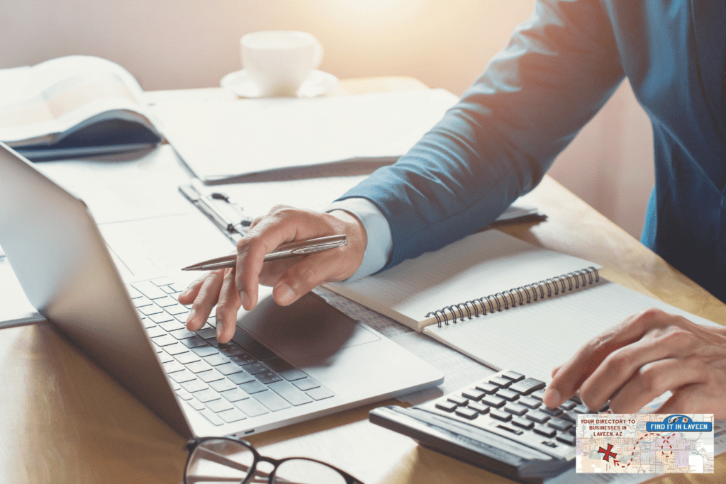 Man working at his desk with a laptop and many papers, books, and notebooks. They look very professional.