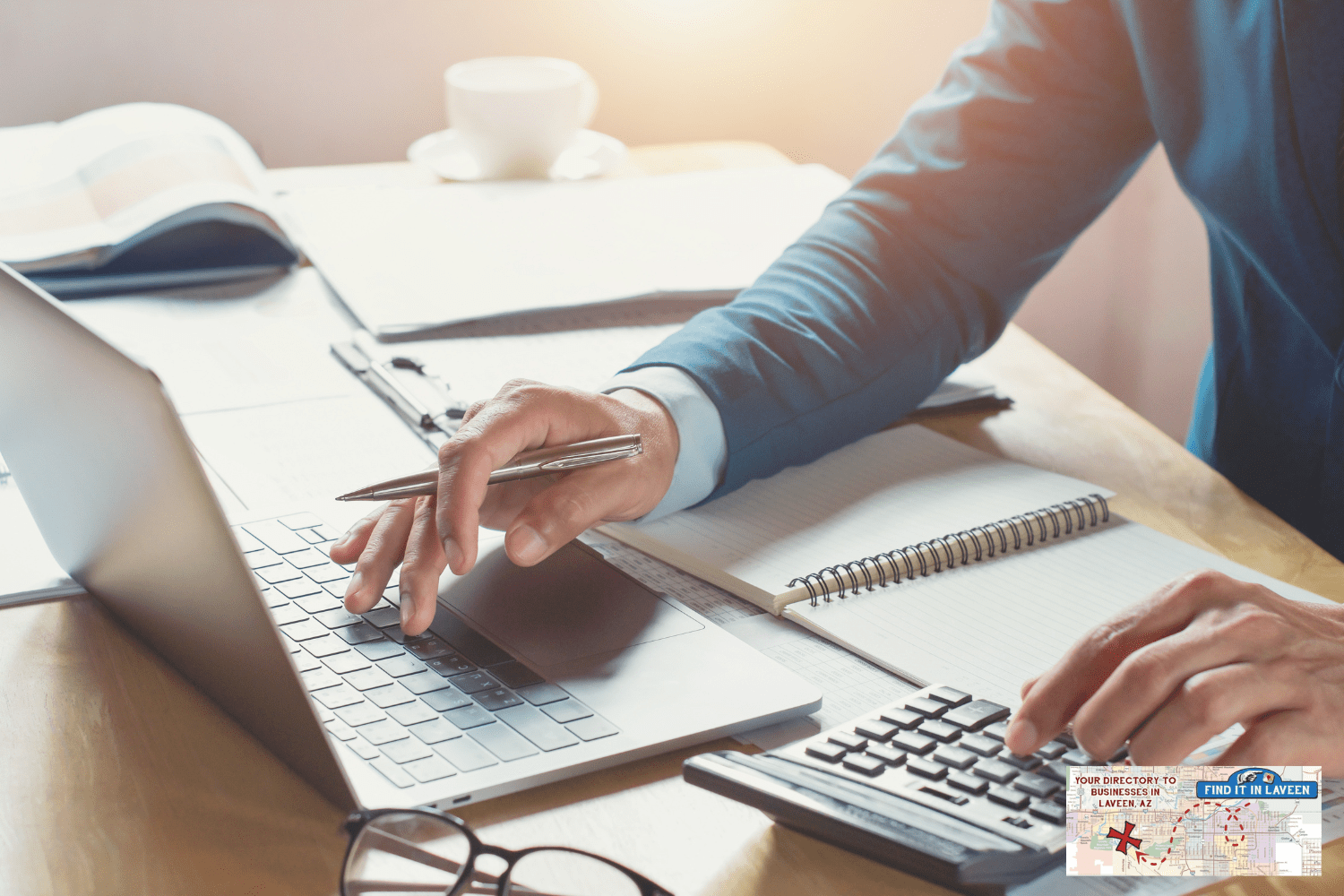 Man working at his desk with a laptop and many papers, books, and notebooks. They look very professional.